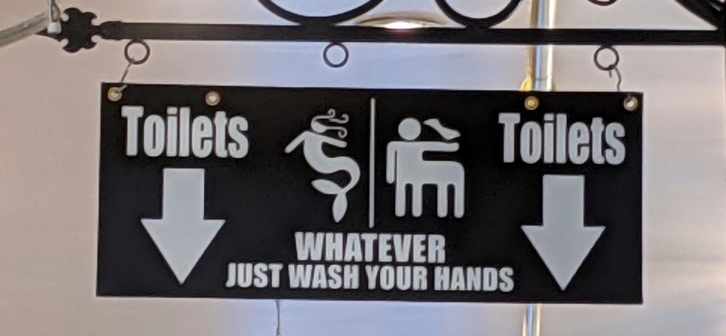 no stress bathroom sign with mermaid and centaur with arrows pointing to toilets, then states, whatever just wash your hands