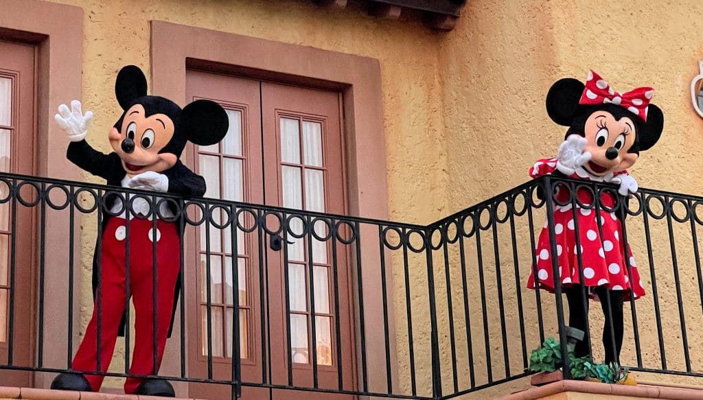 Mickey and Minnie Mouse waving from a balcony at Disney