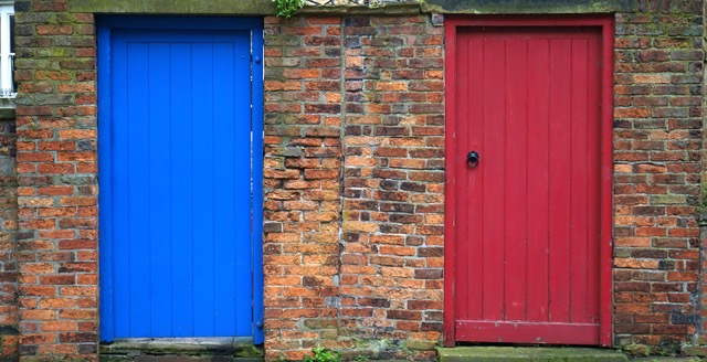 Two doors of opportunity on a brick building. Left door is blue, right door is red. 